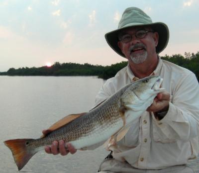 Guy Neff showing off a beautiful slot sized redfish he caught as the sun was begining to appear over the horizon.